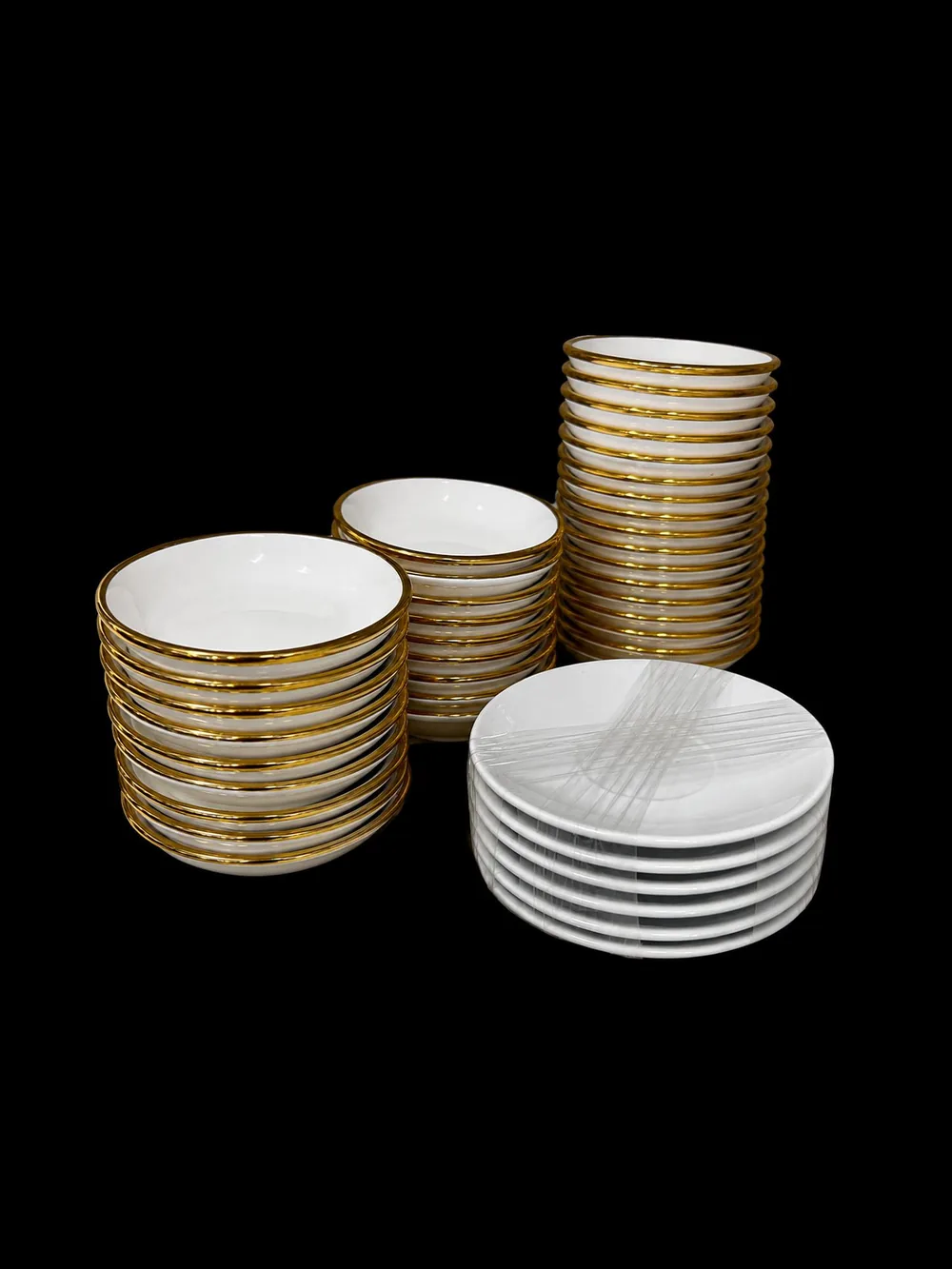 Stacked gold-rimmed porcelain sini coffee cups with white saucers